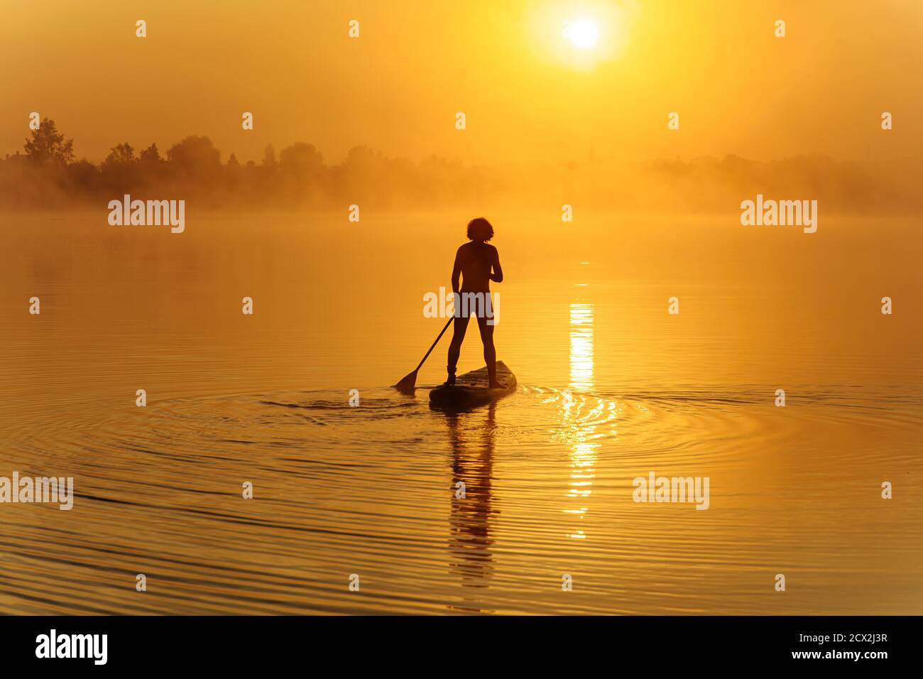 Starker Kerl, der morgens auf dem Paddle Board schwimmt Stockfoto