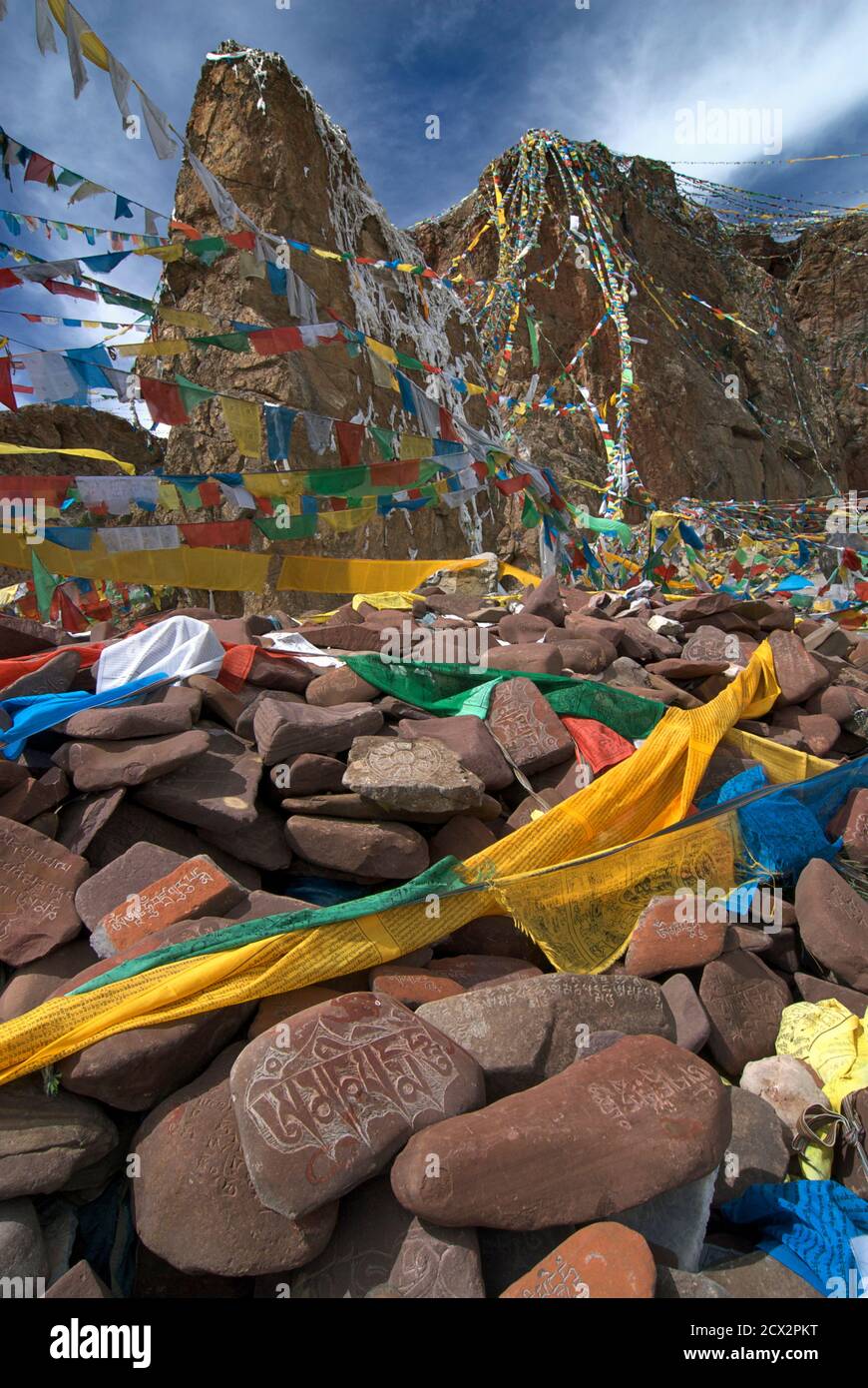 Steine mit buddhistischen Schriften in tibetischer Schrift und Gebetflaggen an einem Kreideplatz neben dem Nam Tso See, Tibet Stockfoto