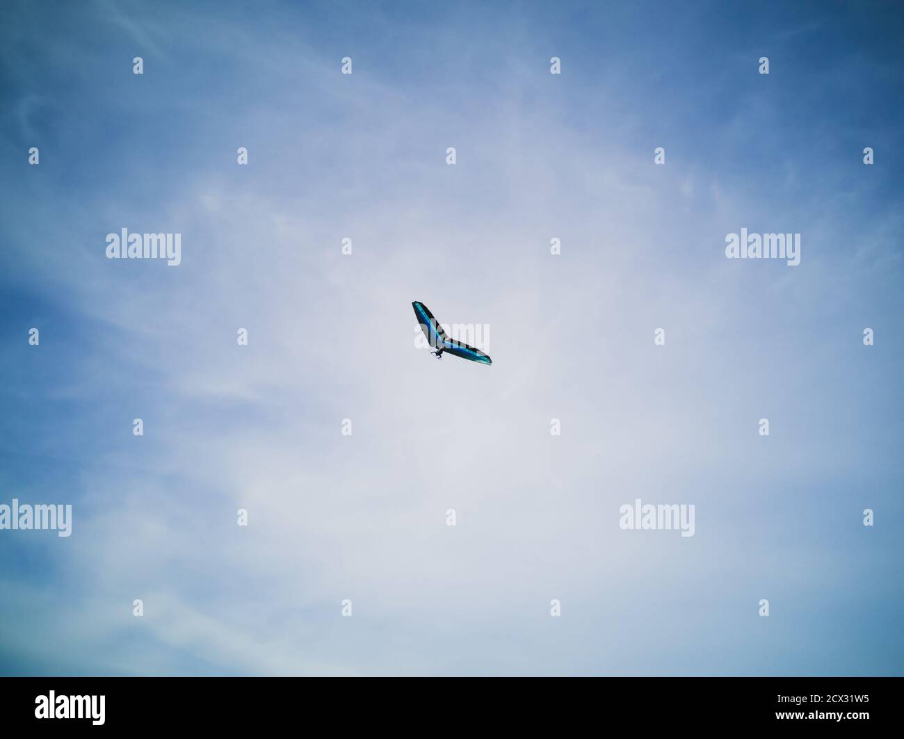 Blauer Gleitschirm, der hoch in einem wunderschönen blauen Himmel mit weißen Zirruswolken in Khodosivka, Kiew fliegt. Extremsport-Hobby. Stockfoto