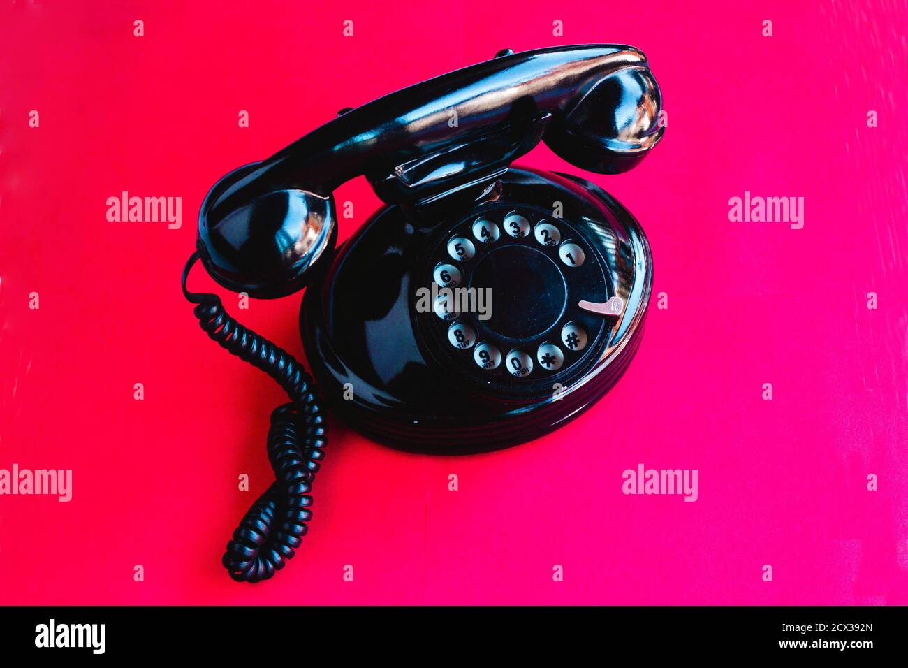 Altes Drehtelefon auf einem rosa und roten Farbverlauf Hintergrund Stockfoto