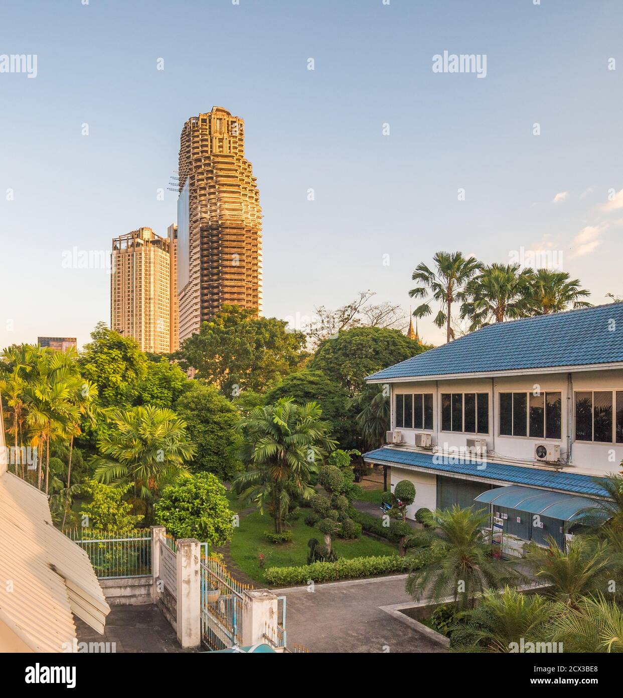 Urbane Szene. Verlassene Wolkenkratzer mit Grün beleuchtet von Golden Light in Bangkok, Thailand. Stockfoto