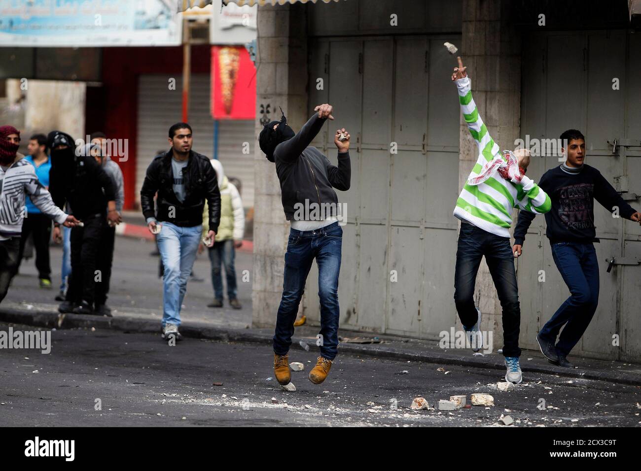 Palästinensische Demonstranten mit Steinen werfen bei Zusammenstößen mit israelischen Truppen in der Westbank-Stadt Hebron 1. März 2013. Der Tod eines palästinensischen Gefangenen unter umstrittenen Umständen in einem israelischen Gefängnis letzte Woche, zusammen mit einem Hungerstreik von vier anderen palästinensischen Gefangenen, von die zwei ihren Protest am Mittwoch beendet nach einer auf ihre Freilassung Einigung mit Israel, haben aus gewalttätigen Protesten in den vergangenen Wochen im Westjordanland berührt. REUTERS/Ammar Awad (Westjordanland - Tags: Politik Unruhen) Stockfoto