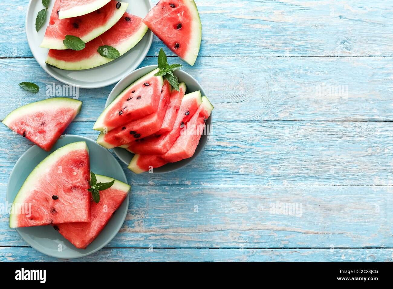 Frische rote geschnittene reife Wassermelone mit Minze auf blauen Tellern. Draufsicht mit Kopierbereich. Sommerkonzept. Stockfoto