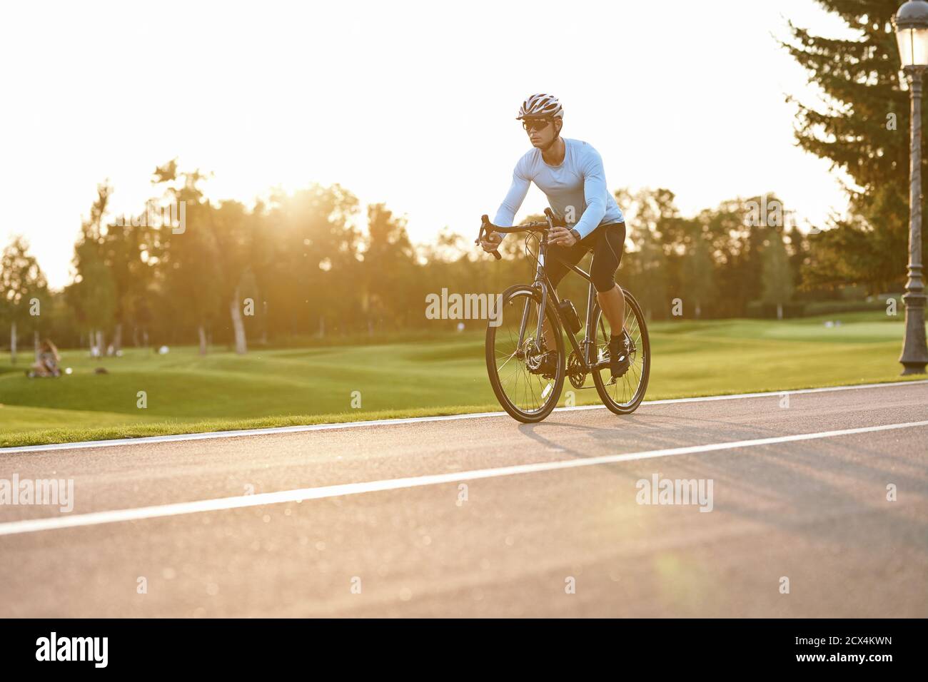 Perfekte Fahrradsaison. Athletic Mann in Sportbekleidung, professionelle Fahrrad-Rennfahrer in Sportbekleidung Reiten Mountainbike im Stadtpark bei Sonnenuntergang. Gesunder aktiver Lebensstil und Sportkonzept Stockfoto