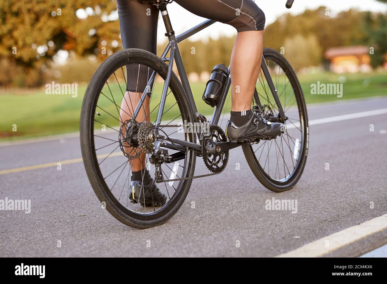 Radfahren im Freien. Eine Aufnahme eines Mannes, der im Freien radelt und mit seinem Fahrrad auf der Straße steht. Konzentrieren Sie sich auf männliche Beine. Aktives Lifestyle- und Sportkonzept Stockfoto