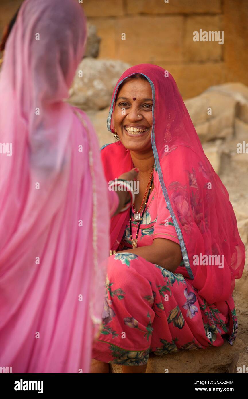 Rajasthani Frauen, die Wasser von einem Brunnen an Amar Sagar, Lodurva, nr Jaisalmer, Rajasthan, Indien tragen. Ein Sari ist ein südasiatisches Frauenkleid, das aus einem Tuch mit einer Länge von 4 bis 8 Metern und einer Breite von 60 bis 1,20 Metern besteht, das normalerweise um die Taille gewickelt ist, wobei ein Ende über die Schulter drapiert ist und das Mittelriff entblößte. Der Sari wird normalerweise über einem Petticoat getragen. Der Sari ist mit Gnade verbunden und gilt weithin als Symbol der indischen Kultur. Stockfoto