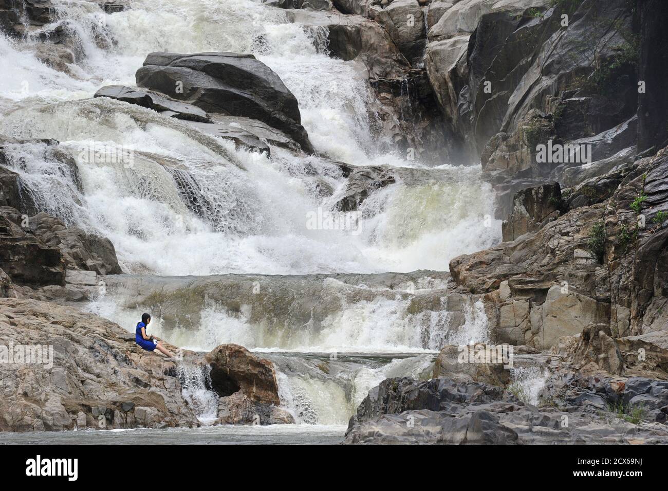 Tourist sitzt auf den Felsen am Ba Ho Wasserfall, Nha Trang, Vietnam Stockfoto