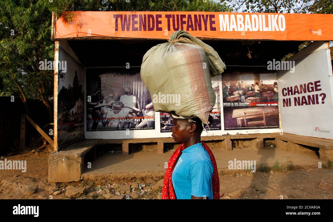 Eine Frau geht vorbei an einer Bushaltestelle, die liest "lassen Sie uns gehen und Wandel", Förderung der friedliche Wahlen in Kenia der westlichen Stadt Kisumu, 350 km (218 Meilen) von der Hauptstadt Nairobi, 6. März 2013. Kenia Zuflucht zu Hubschrauber fliegen Beamten tragen Ergebnisse vom Präsidenten Umfrage dieser Woche in die Hauptstadt, lassen Sie sich durch neue Technologien zur Vermeidung der gewaltsamen Auseinandersetzungen, die 1.200 Todesfälle nach der Abstimmung vor fünf Jahren geführt. REUTERS/Thomas Mukoya (Kenia - Tags: Gesellschaft Politik Wahlen) Stockfoto