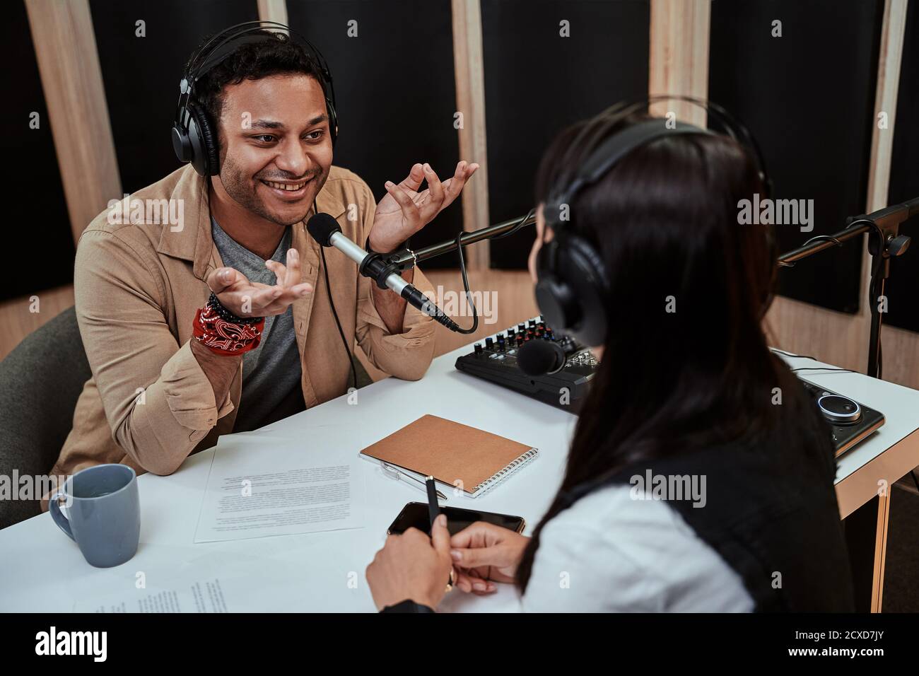 Portait von glücklichen männlichen Radiomoderator lächelnd, im Gespräch mit weiblichen Gast während der Moderation einer Live-Show im Studio Stockfoto