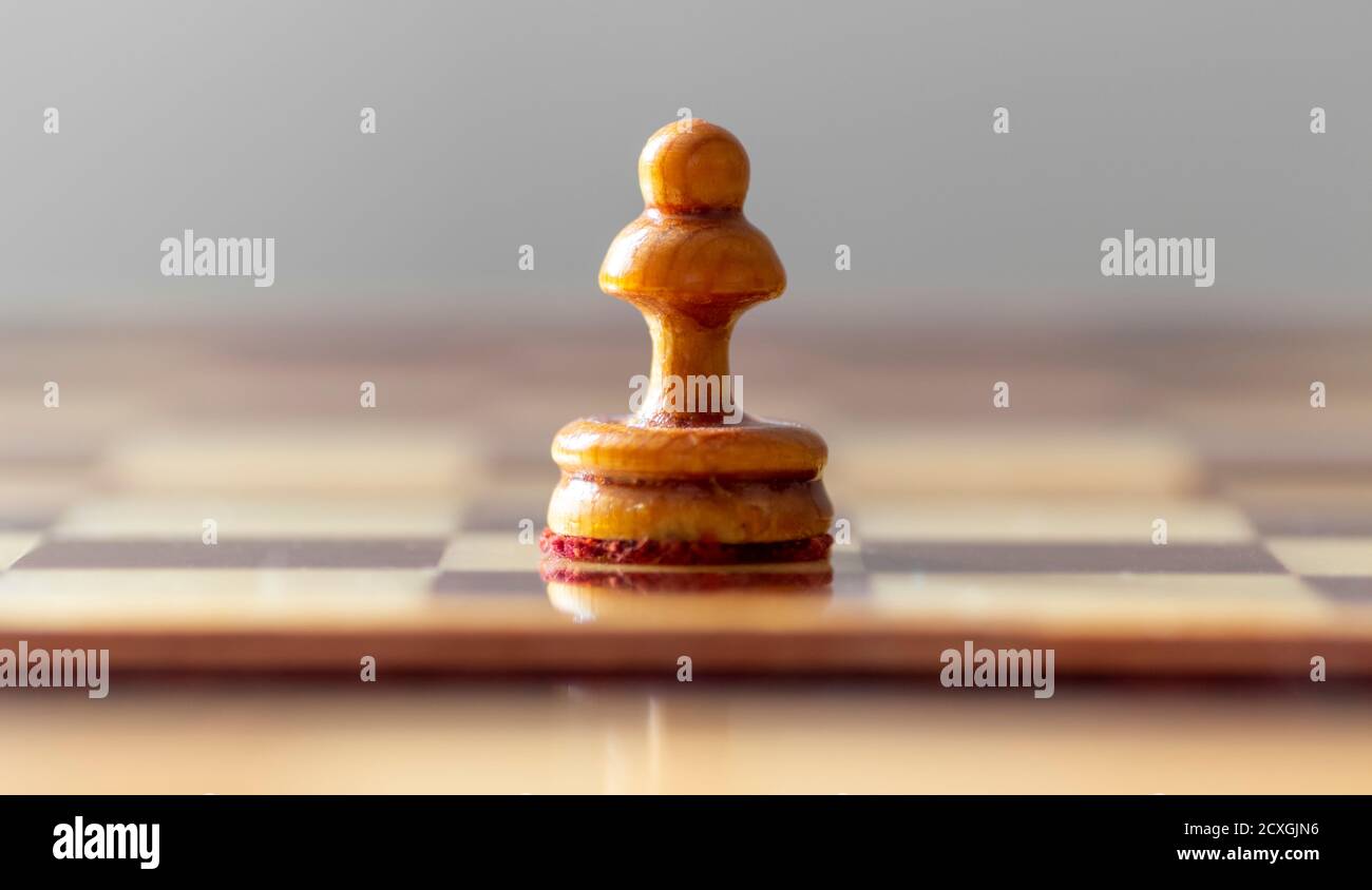 Ein Bauer steht auf einem leeren Schachbrett. Stockfoto