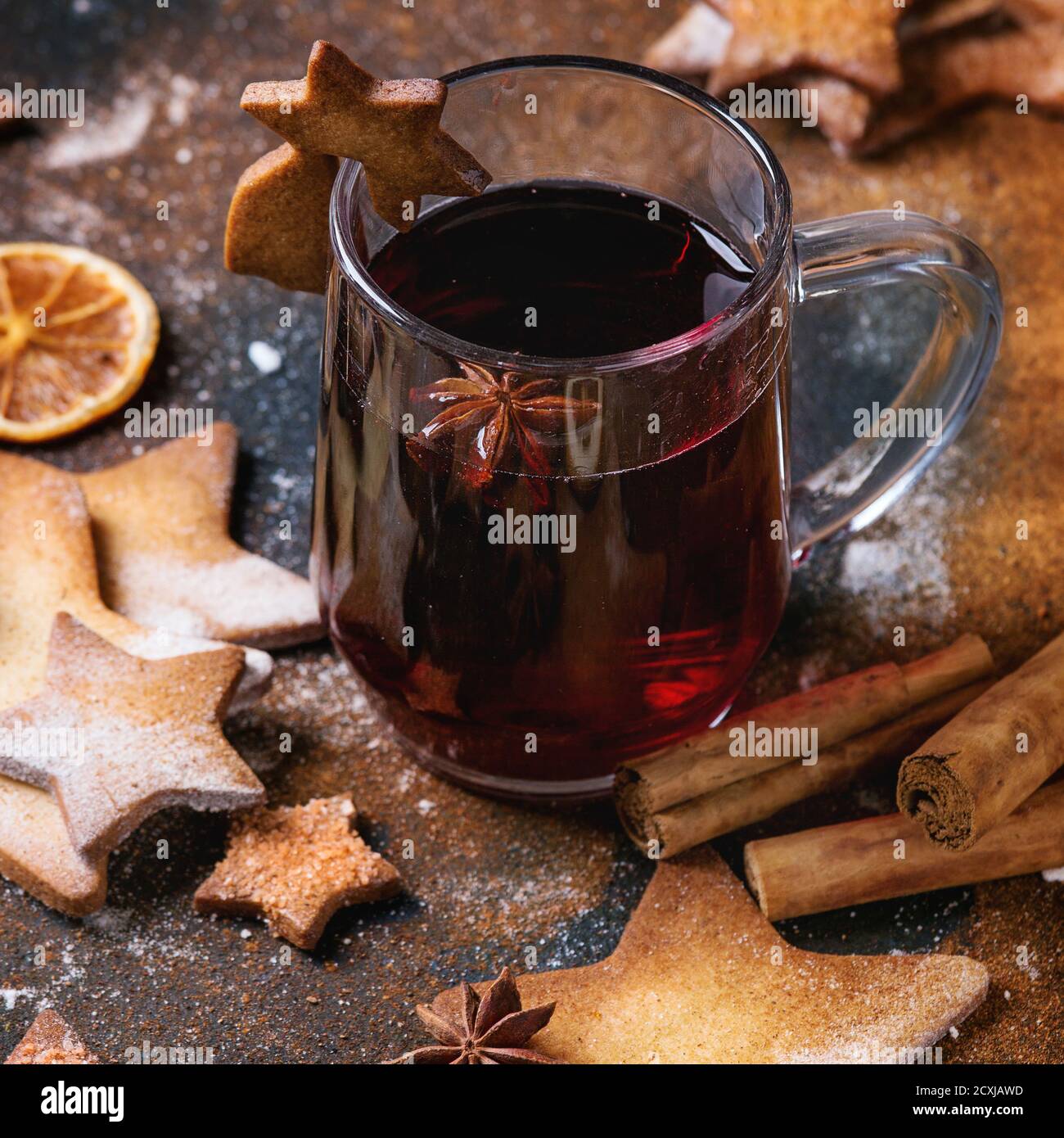 Glaskrug mit heißen roten Glühwein Gewürze, Zucker Shortbread Cookies Stern Form und Cookie auf Glas, Anis und Zimt Pulver über dunkel strukturierte Backgro Stockfoto