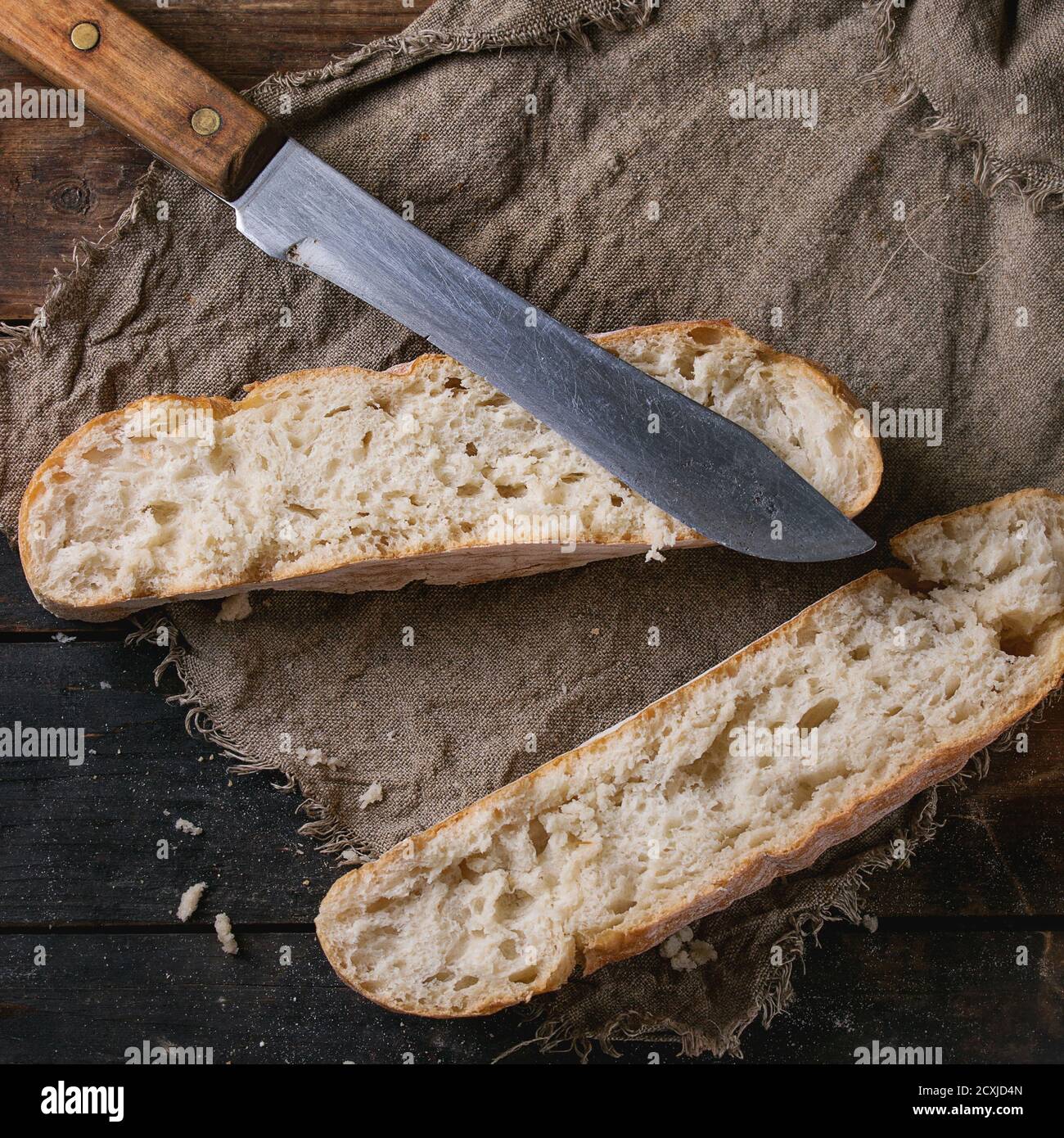 Laafs frisch gebackenes handwerkliches Brot auf Sacktuch mit Vintage-Messer über altem Holzhintergrund. Overhead-Ansicht. Quadratisches Bild Stockfoto