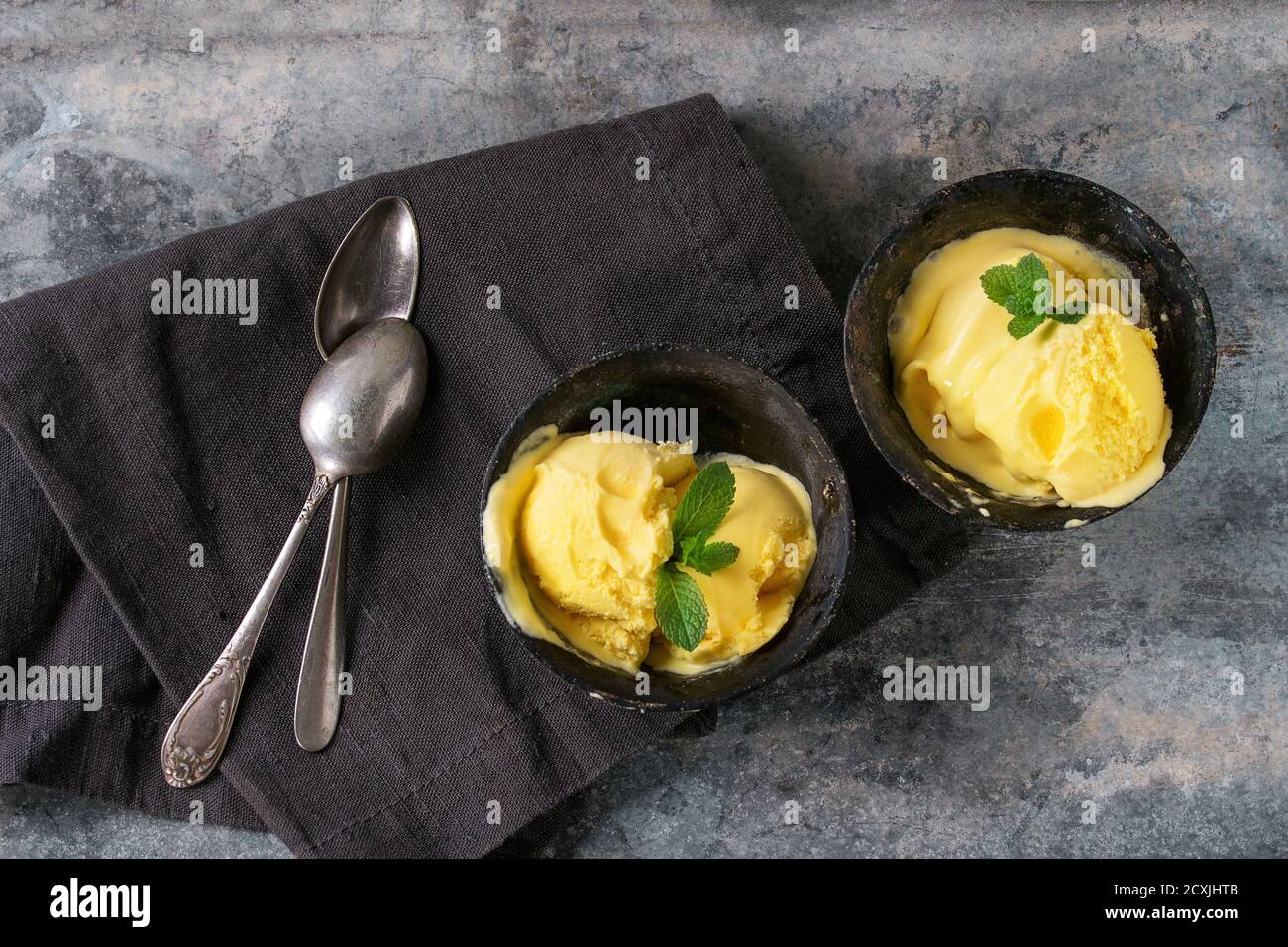 Hausgemachte Mango-Eis mit frischer Minze in Vintage Eisen Schalen über grau Metall strukturierten Hintergrund. Flach zu legen Stockfoto