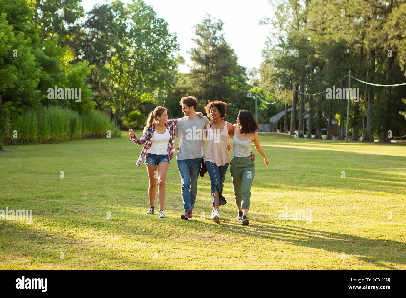 Glückliche junge Freunde, die zusammen im Park spazieren Stockfoto