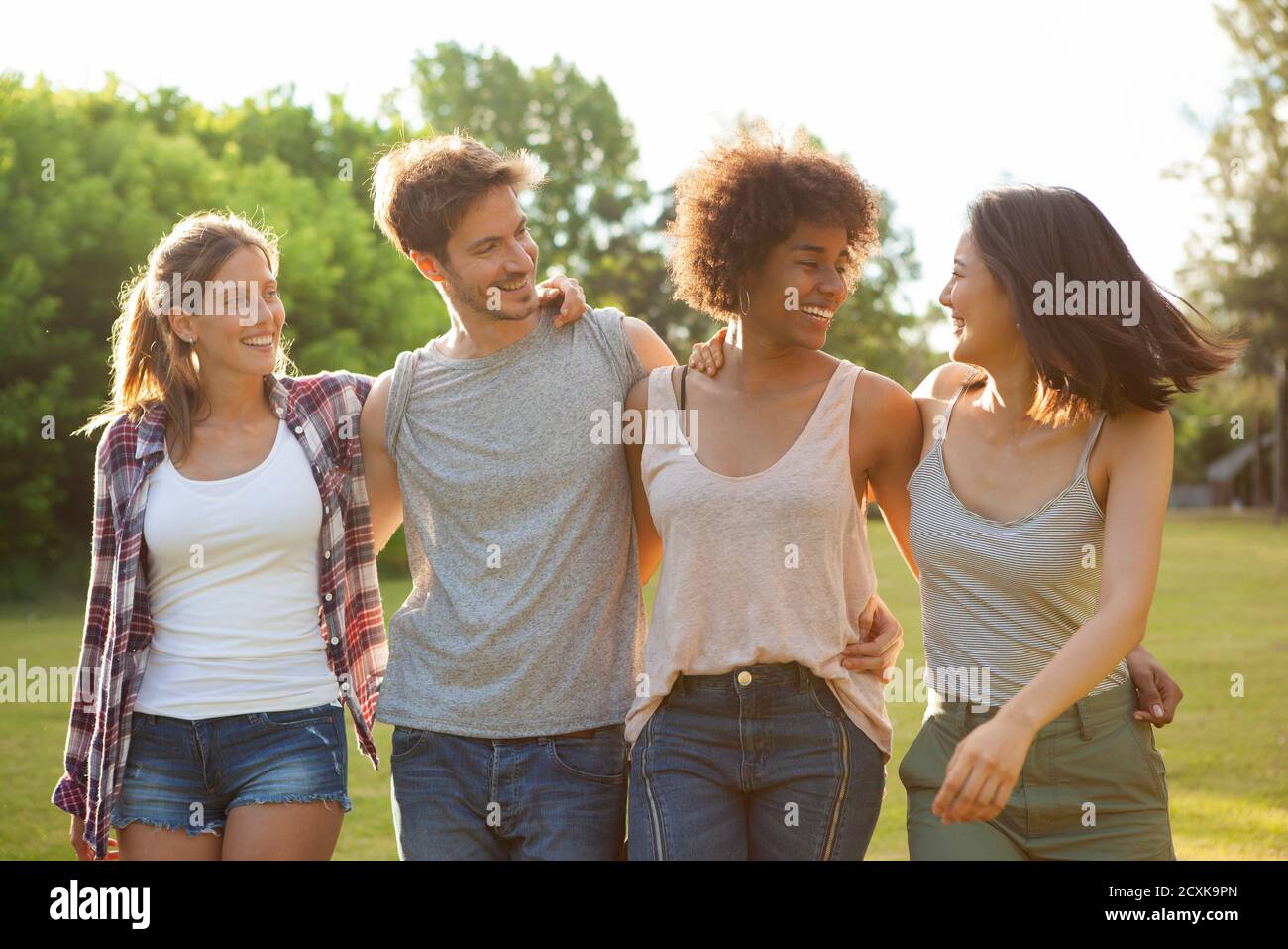 Glückliche junge Freunde, die zusammen im Park spazieren Stockfoto