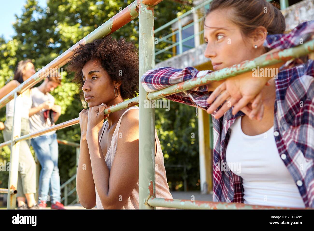 Nachdenkliche junge Frau, die mit ihren Freunden im Freien sitzt Stockfoto