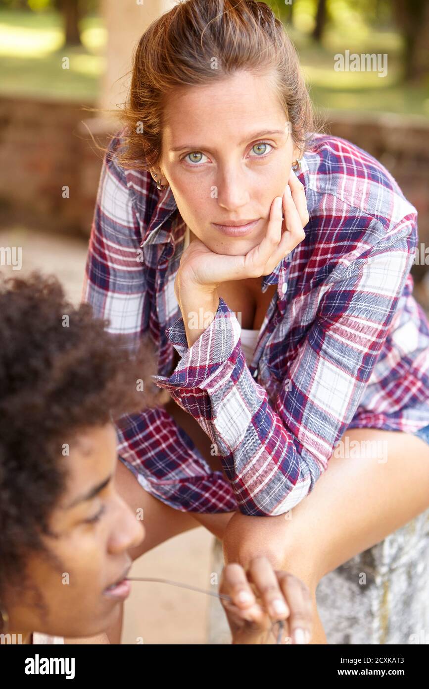 Schöne junge Frau sitzt im Freien Stockfoto