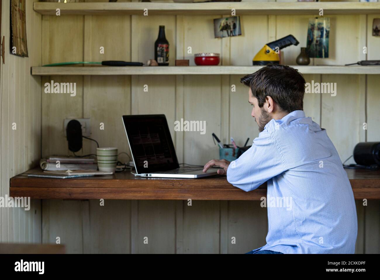 Junger Mann mit Laptop im Wohnzimmer Stockfoto