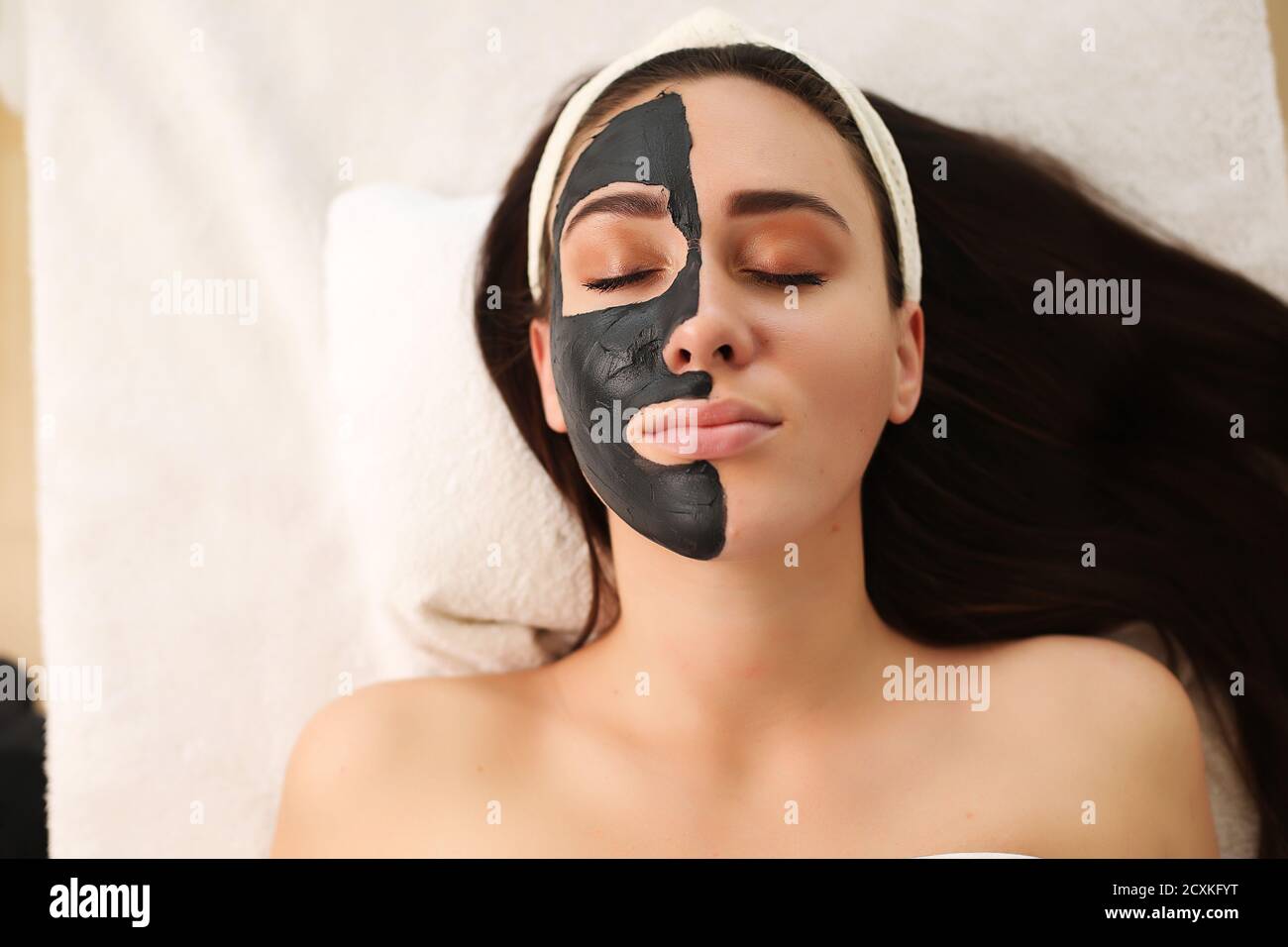 Schöne Frau mit Ton Gesichtsmaske von Kosmetikerin anwenden. Stockfoto