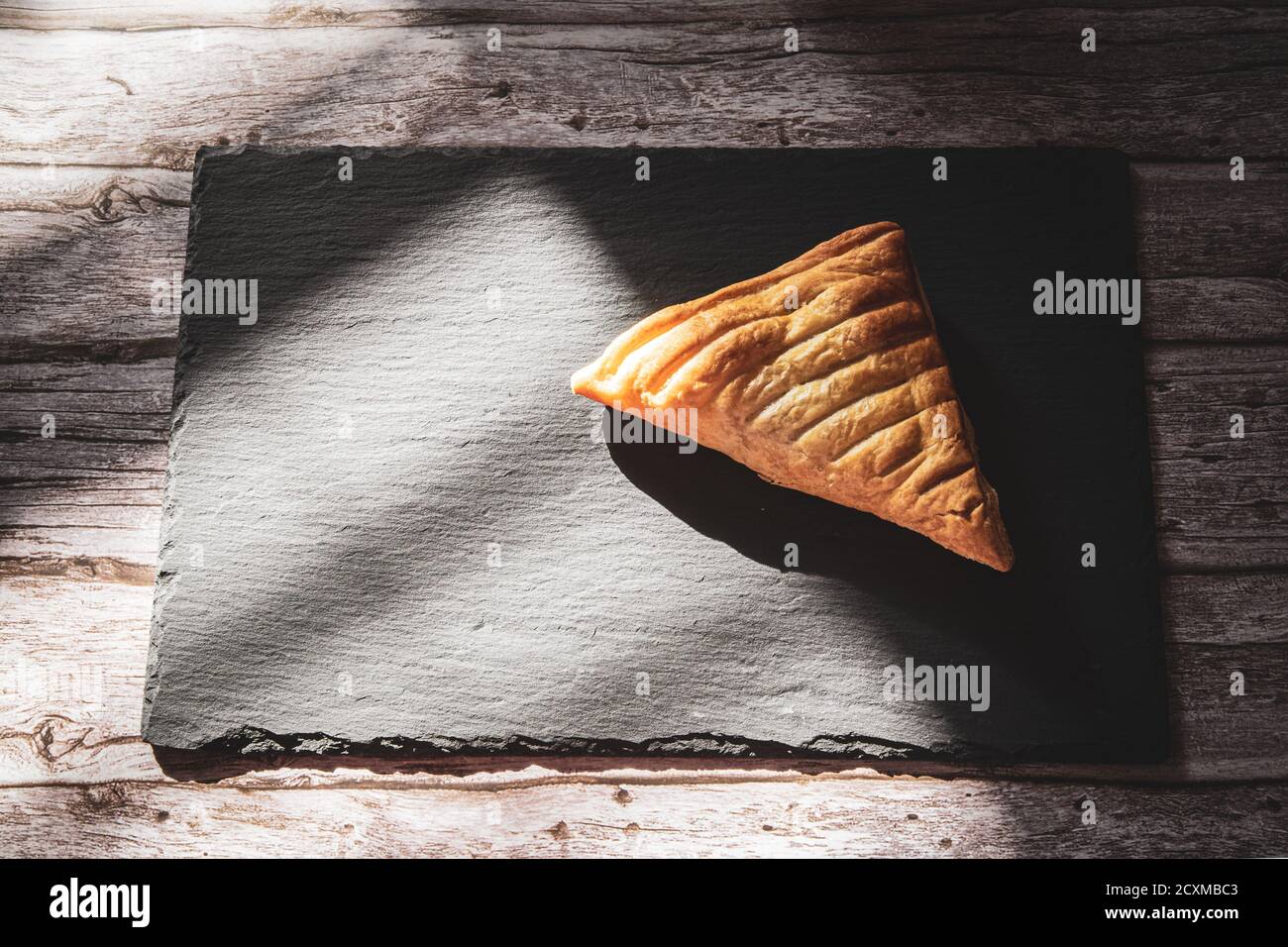 Ein frisches Apfelkuchen Gebäck auf einem Schieferbrett ruht Auf einem rustikalen Holztisch Stockfoto