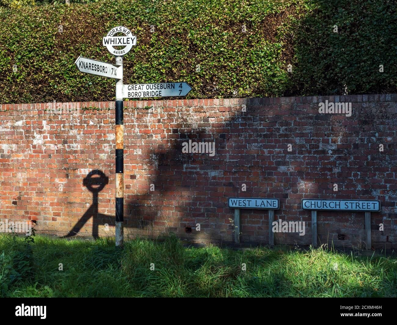 Old West Riding of Yorkshire Rundschild mit Dorfnamen Und Gitterreferenz durch eine Ziegelwand in Whixley in der Nähe Knaresborough North Yorkshire Engla Stockfoto