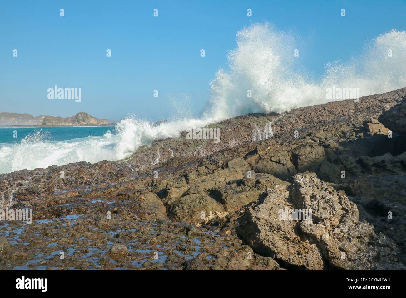 Wellen planschen auf einer Landzunge rund um den Strand von Tanjung Aan. Gefährliches Phänomen an einem himmlischen Strand. Wasser wird durch die Stärke der Zerkleinerung sprudelt Stockfoto