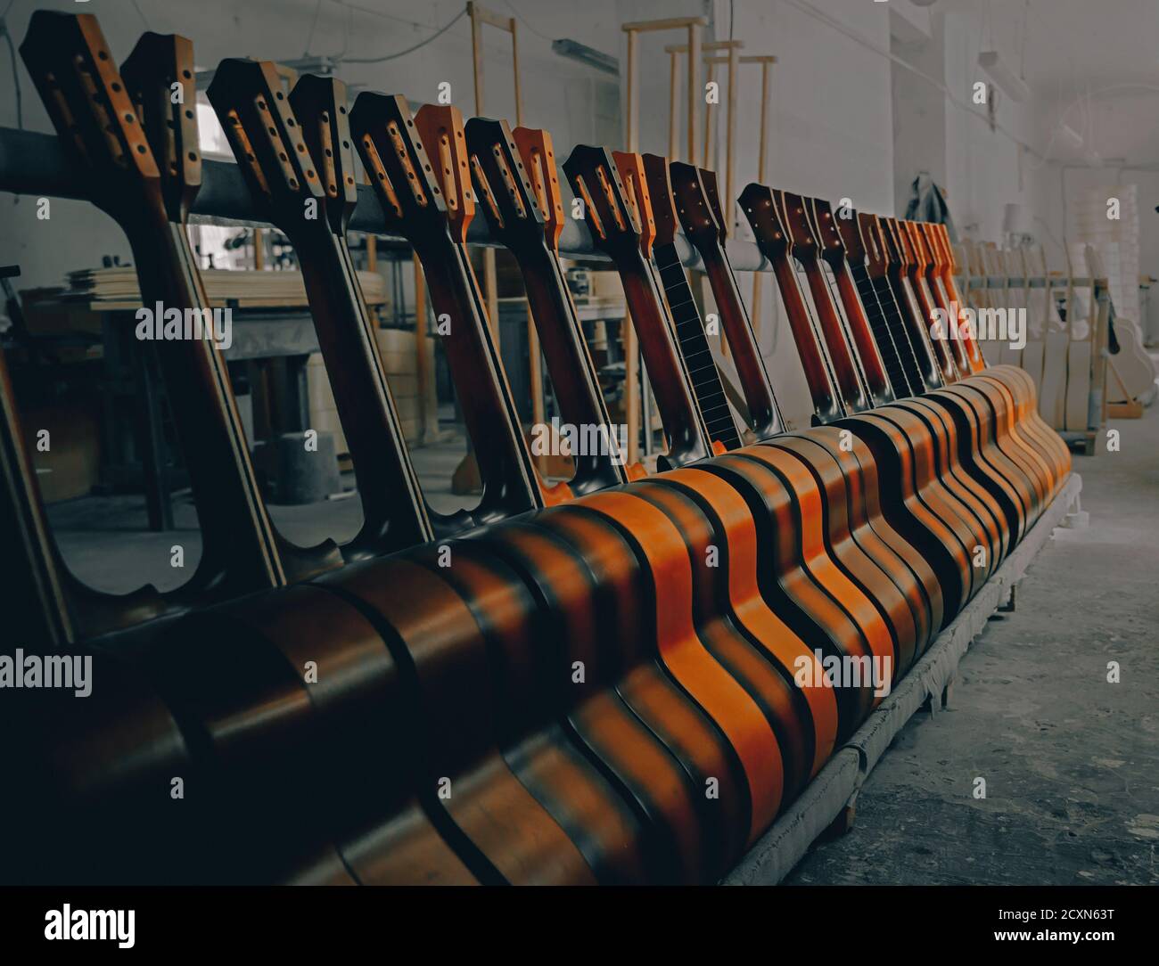 Akustische Gitarren stehen in Reihen. Nahaufnahme der Gitarren in einer Reihe bei Workshop, Musik Instrumental Konzept. Geringe Schärfentiefe. Stockfoto