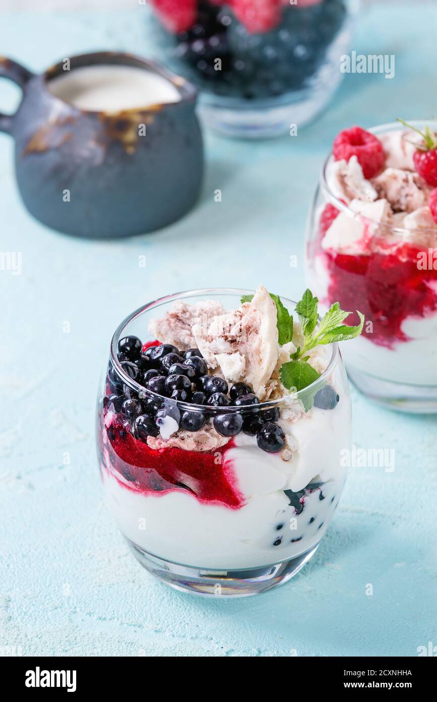 Traditionelle Sommer dessert Eton Mess. Gebrochene Meringue mit Schlagsahne, Beeren Marmelade, frischen Heidelbeeren und Himbeeren in zwei Gläser, dekoriert mit Stockfoto
