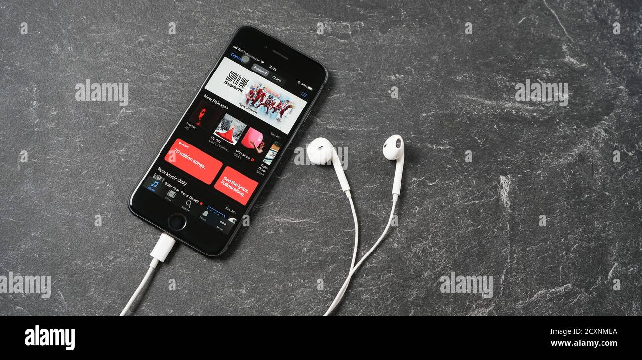 Mataram, Indonesien - 1. Oktober 2020: Apple iPhone 8 mit Apple itunes Musik-App auf dem Bildschirm mit Kopfhörern auf Steinplatte, Draufsicht. Stockfoto