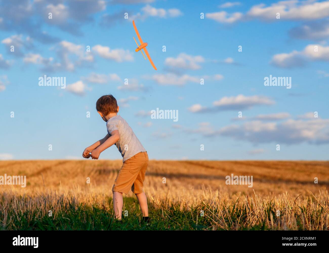 Happy Kind läuft mit Spielzeug Flugzeug auf Himmel Hintergrund glücklich Familie Konzept. Kindheitstraum Stockfoto