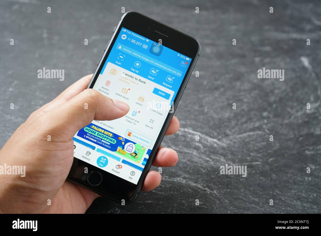 Mataram, Indonesien - 1. Oktober 2020: Hand hält Apple iPhone 8 mit dana App auf dem Bildschirm auf Stein Pad, Draufsicht. Stockfoto