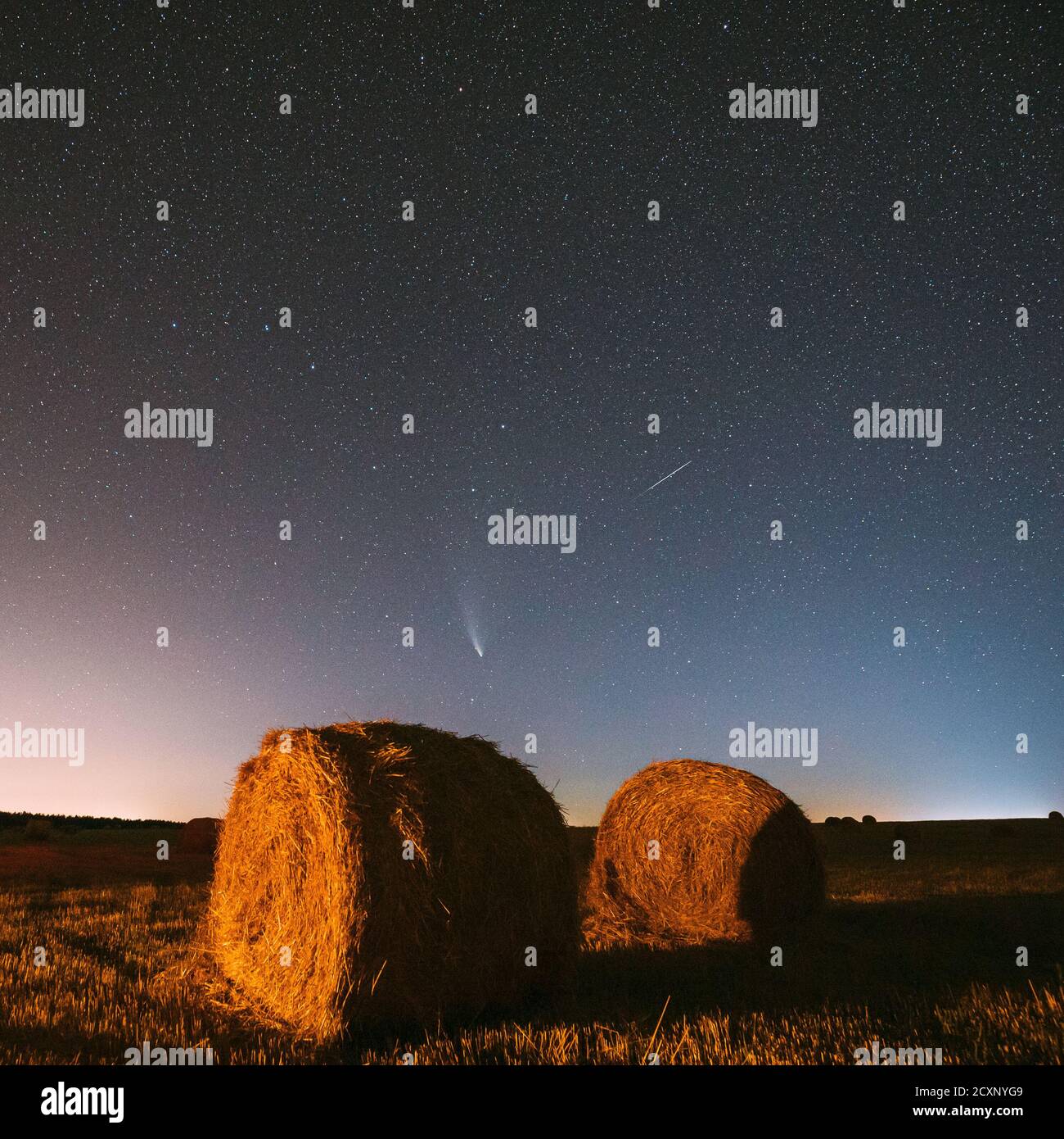 Meteor und Komet Neowise C2020 F3 in der Nacht Sternenhimmel über Haystacks im Sommer landwirtschaftlichen Feld. Nachtsterne Über Der Ländlichen Landschaft Mit Heuballen Stockfoto