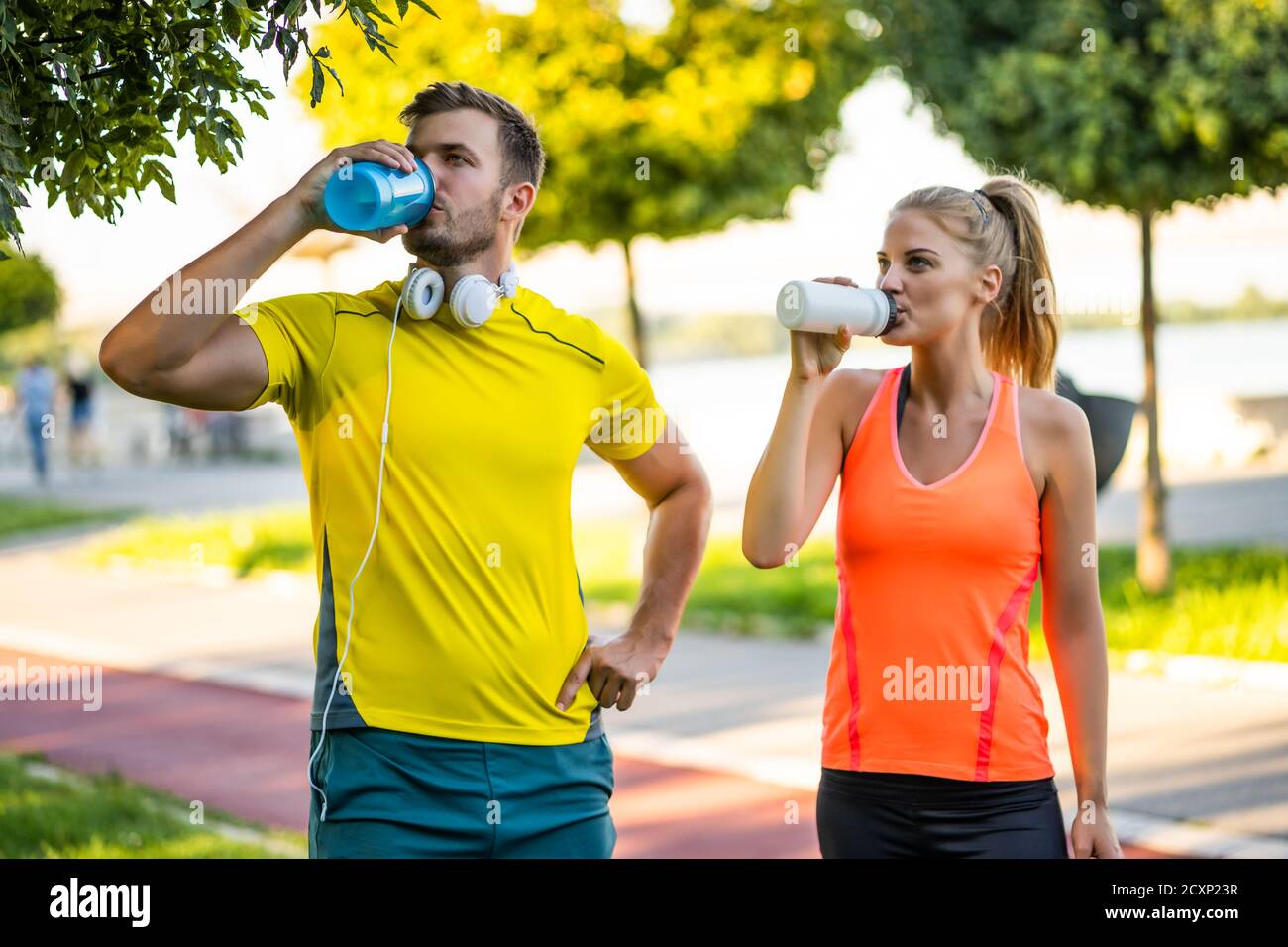 Das junge Paar trinkt Wasser während des Trainings im Freien. Stockfoto