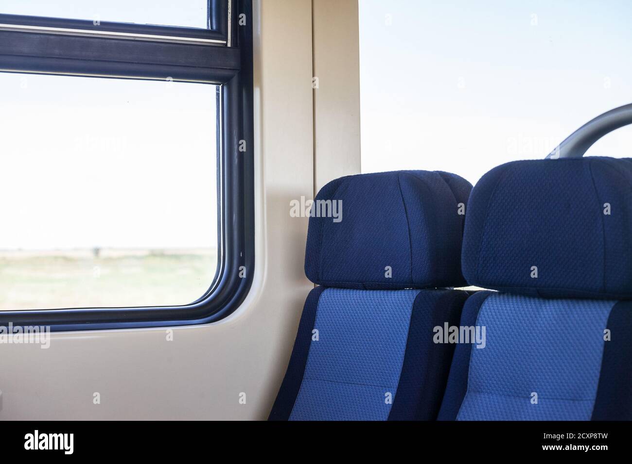 Leere Sitze in einem modernen Regionalzug, im europäischen Stil, auf einer Fahrt in einer Landschaft mit einem Geschwindigkeitsunschärfe-Effekt aus dem Fenster. Bild eines Typi Stockfoto
