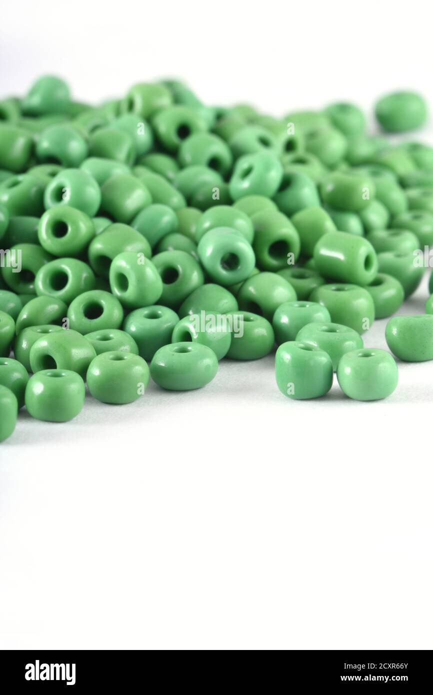 Nahaufnahme der grünen Perlen auf dem weißen Hintergrund. Hintergrund oder Textur von Perlen. Makro, Es wird in der Finishing Mode Kleidung verwendet. Machen Perlen Halskette oder Stockfoto