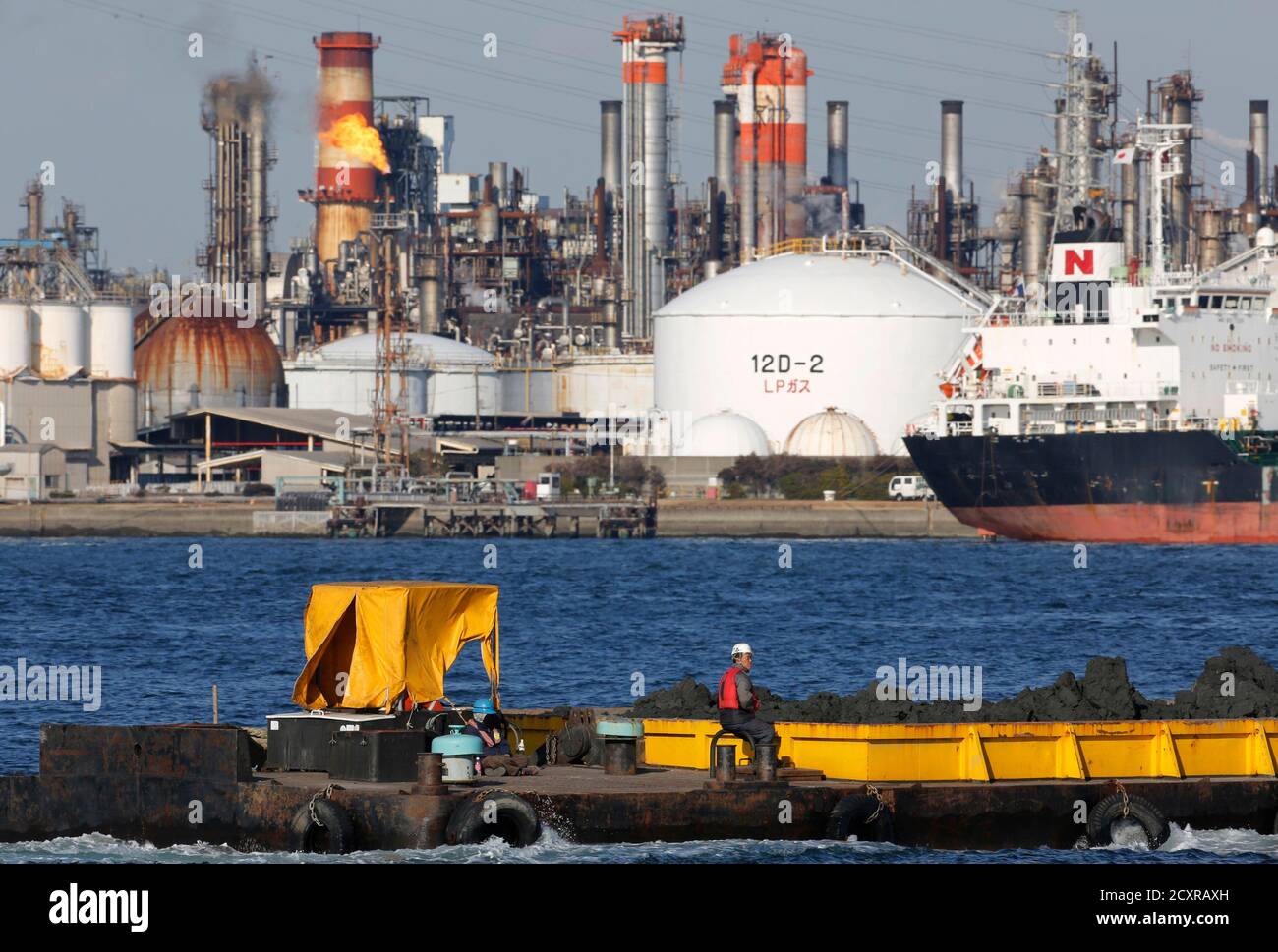 Männer an Bord eine Kies-Carrier übergeben durch eine Öl-Raffinerie in Kawasaki, südlich von Tokio 30. Januar 2013. REUTERS/Toru Hanai (JAPAN - Tags: BUSINESS ENERGY) Stockfoto