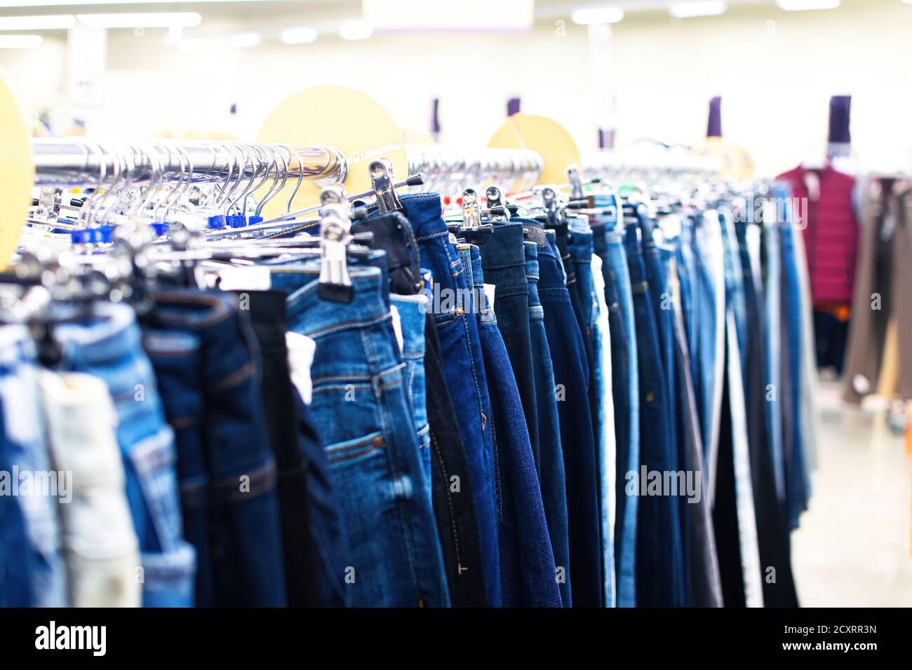 Eine Reihe von Damen Denim-Hosen auf einem Kleiderbügel im Geschäft. Verkauf von Jeans im Geschäft. Selektiver Fokus. Stockfoto