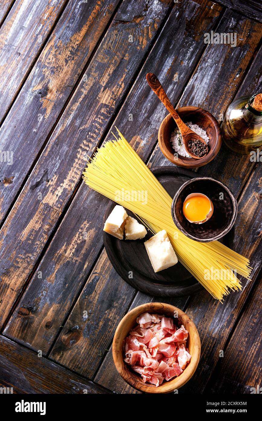 Zutaten für traditionelle italienische Pasta alla Carbonara. Ungekochte Spaghetti, bauchspeck Speck, Parmesan, Eigelb, Salz, Pfeffer in Olivenholz bo Stockfoto