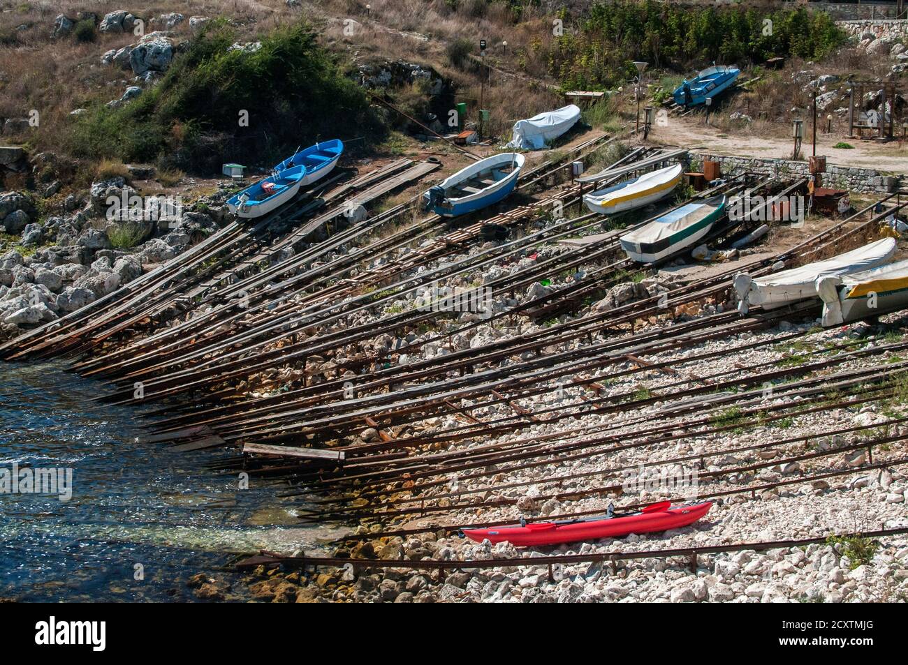 Steilküste von kleinen Fischerbucht mit Einrichtungen Boote aus dem Wasser am Ufer zu ziehen Stockfoto