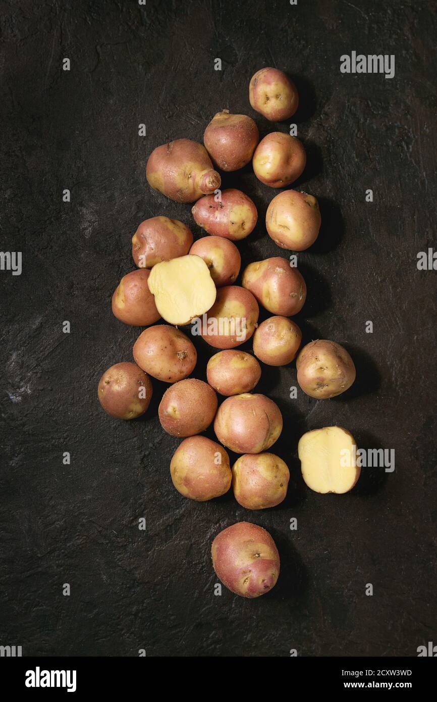 Roh ungekocht Biokartoffeln namens miss Blush, ganze und Schicht über dunkle Textur Hintergrund. Ansicht von oben, kopieren Raum Stockfoto