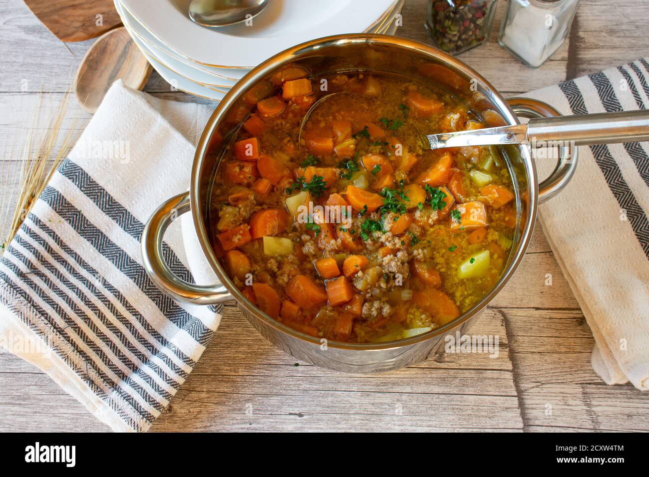 Gemüsesuppe mit Hackfleisch in einem Topf mit Schöpfkelle Auf Holztisch Stockfoto