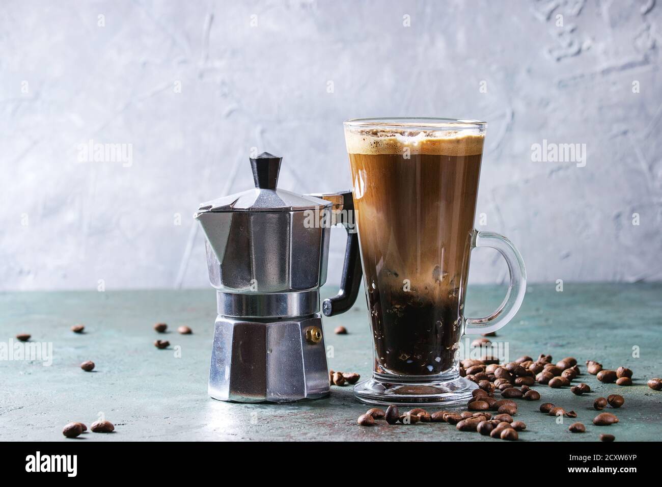 Fizzy Eiskaffee Espresso mit Milch, Kaffeemaschine und gerösteten Bohnen um über Grau Grün Textur Tabelle. Moderne trinken. Platz kopieren Stockfoto