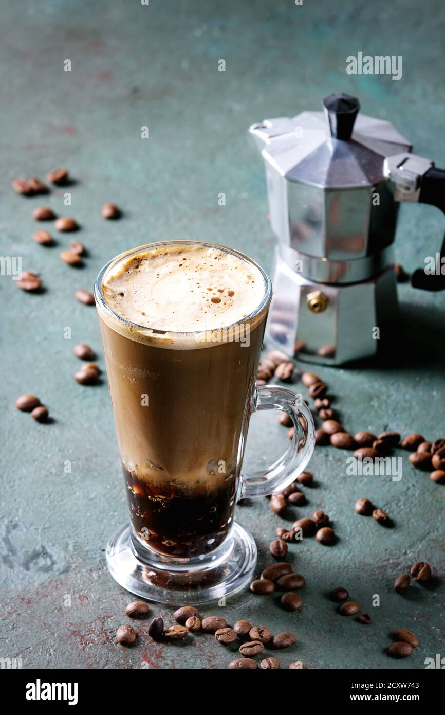 Fizzy Eiskaffee Espresso mit Milch, Kaffeemaschine und gerösteten Bohnen um über Grau Grün Textur Hintergrund. Moderne trinken. Stockfoto