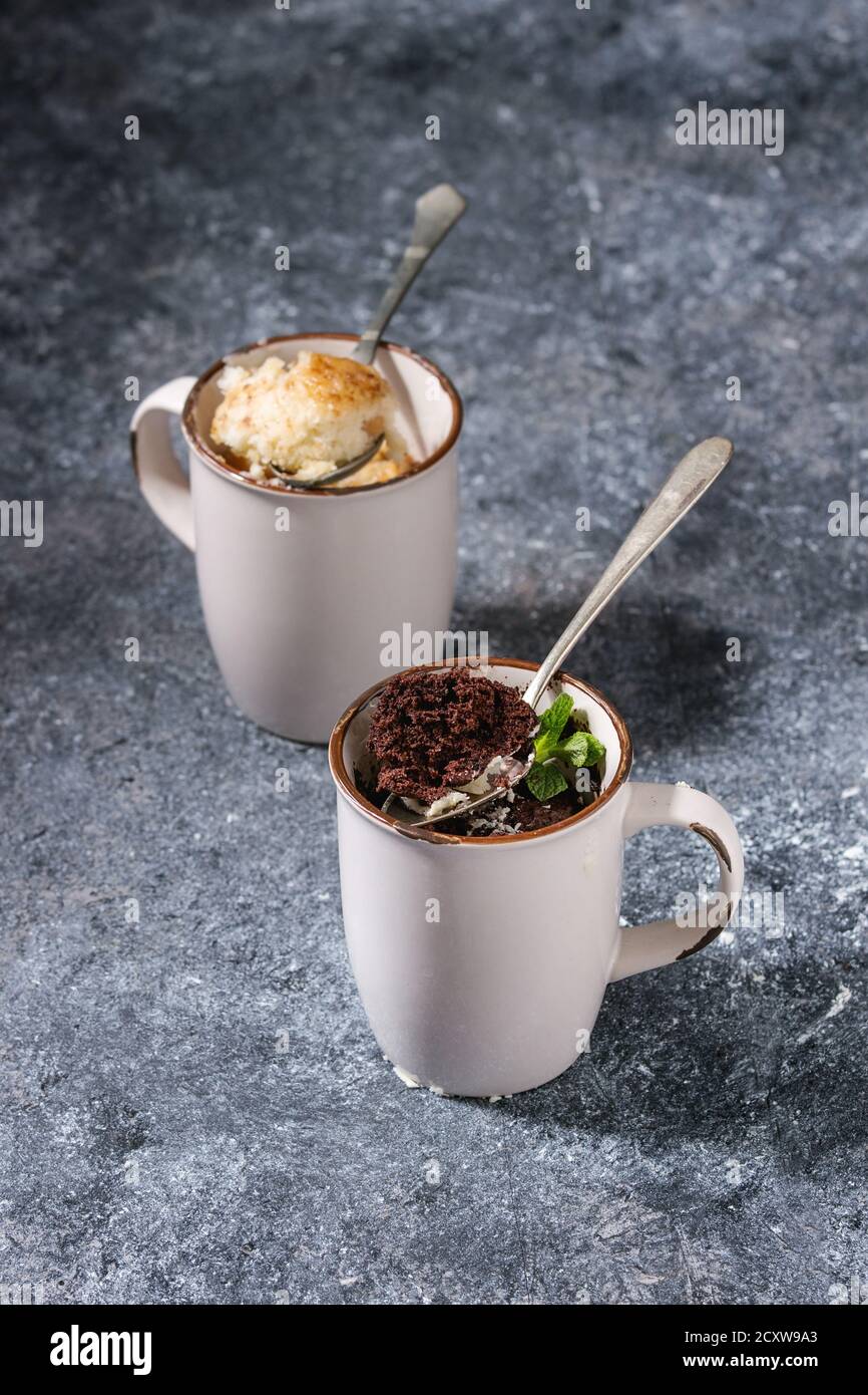 Schokolade und Vanille Karamell Becher Kuchen aus der Mikrowelle mit Löffel über blau Küchentisch. Stockfoto