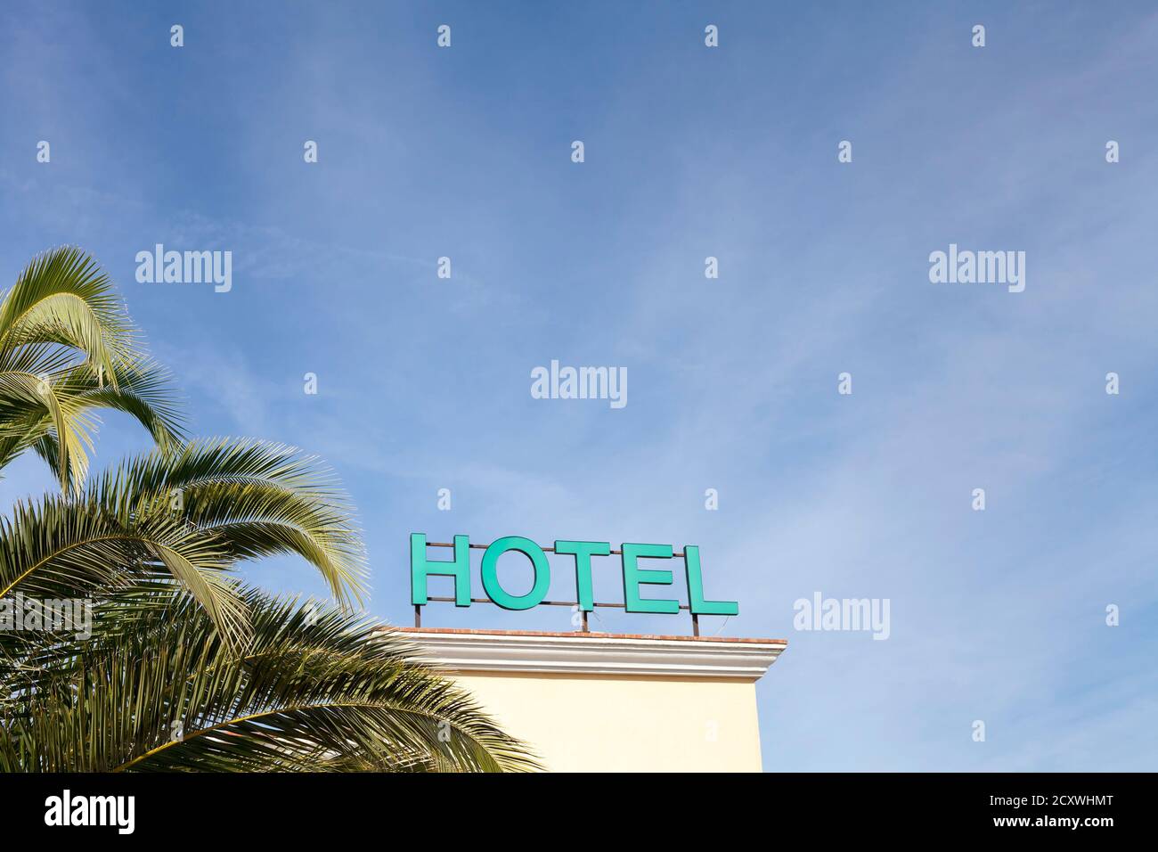Hotelschild mit Palmenblättern und blauem Himmel Tropisches Paradies Stockfoto