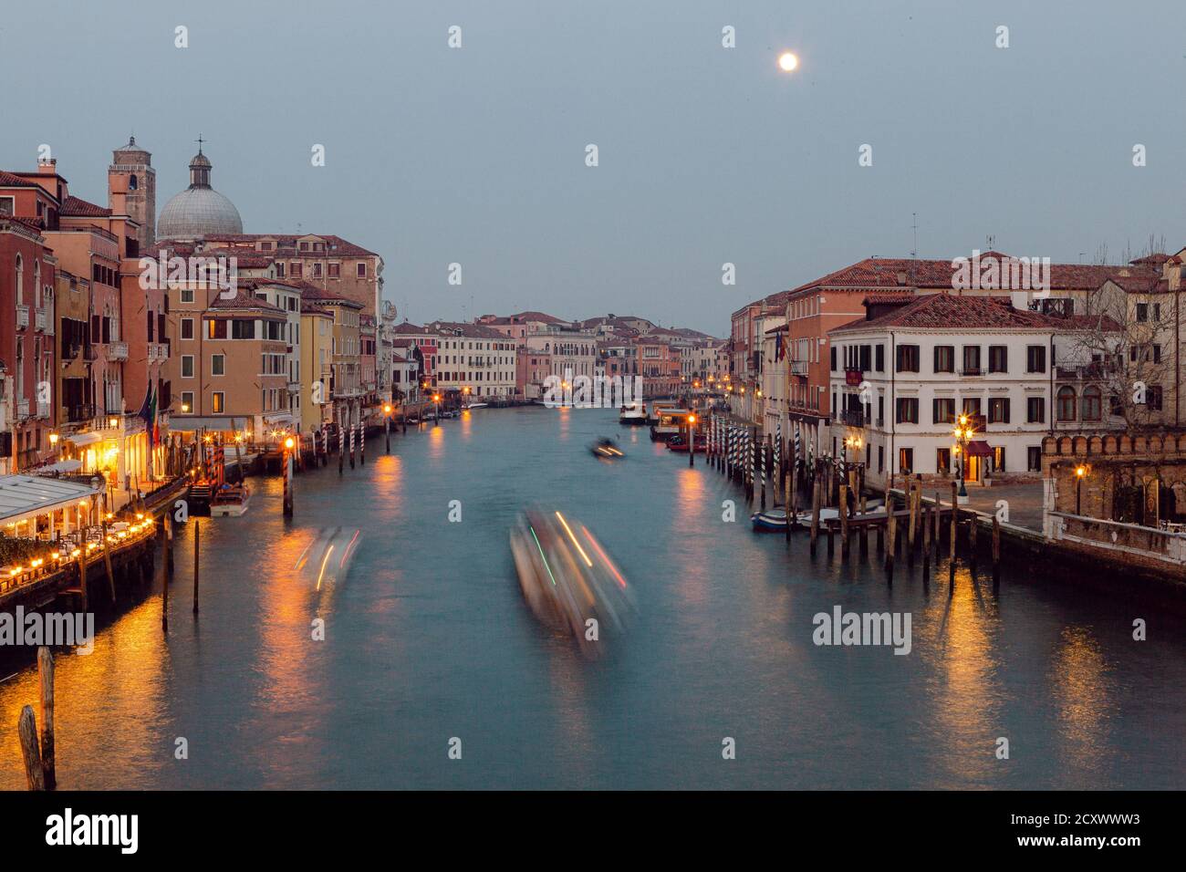Nachtleben in Venedig: Langzeitblick über den Canale Grande, mit Booten, künstlichen Lichtern und langsamem Stadtverkehr Stockfoto
