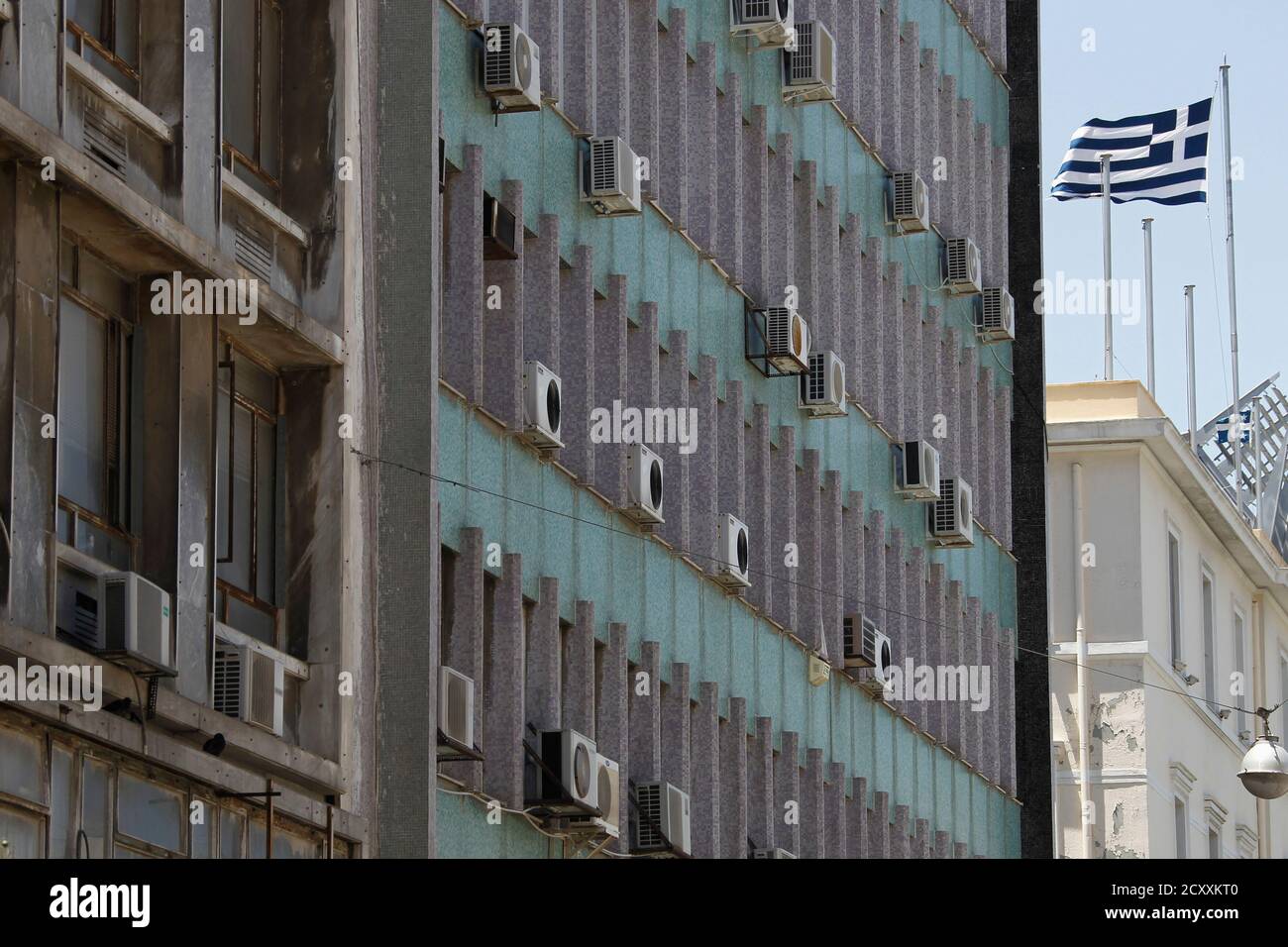 Eine griechische Flagge flattert neben einer Gebäudefassade mit Klimaanlagen in Athen 22. Juni 2012. Stromhändler in mindestens vier Ländern verringert oder gestoppt Stromexporte nach Griechenland aufgrund ausbleibender Zahlung, dazu beitragen, die Marktpreise in einem potenziellen Schlag deutlich höhere Kraft zu kämpfen, Branchen und erhöhen das Risiko von Stromausfällen während der touristischen Saison. REUTERS/Yorgos Karahalis (Griechenland - Tags: Energie-Wirtschaft-Politik) Stockfoto