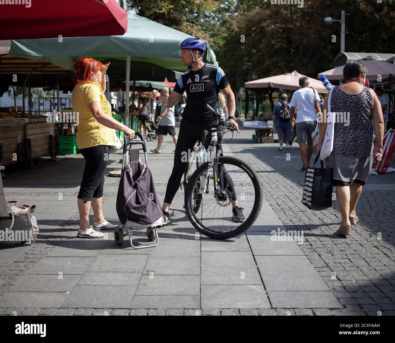 Belgrad, Serbien, 17. Sep 2020: Straßenszene mit einer Frau, die sich mit dem Radfahrer auf dem Bauernmarkt unterhielt Stockfoto