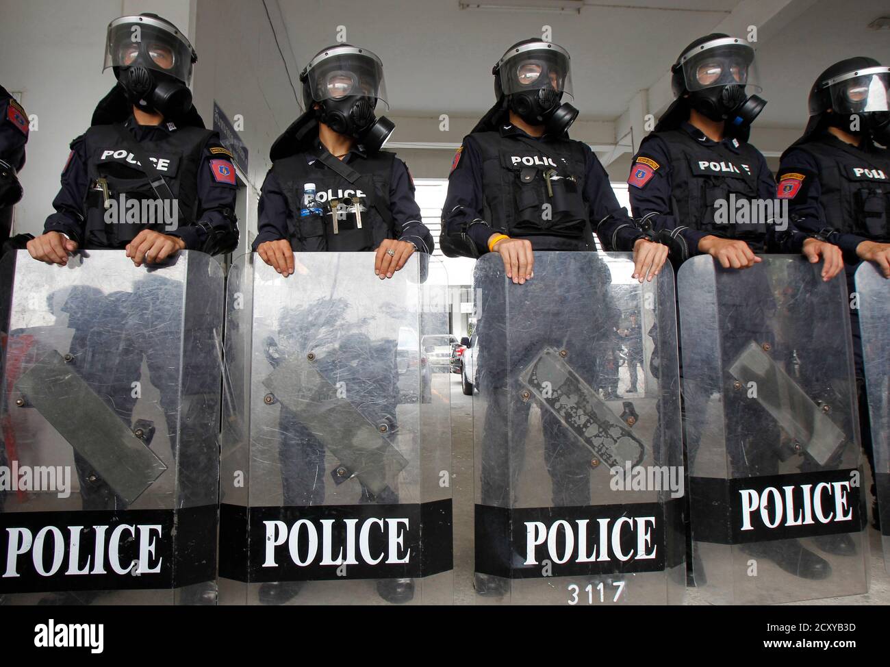 Riot Polizei Offiziere, Gasmasken, stehen mit ihren Schilden während einer Demonstration für die Medien im Royal Thai Police Sport Club in Bangkok 7. Januar 2014. Polizei organisiert die Medien-Demonstration, Tränengas und Gummigeschossen zu präsentieren, die einzige Art von Waffen, die Behörden sagen, für die Kontrolle von Menschenmengen Situationen verwendet wird. Polizei fügte hinzu, dass kein Aufruhr Polizisten dürfen scharfe Munition zu tragen. Laut den Behörden werden 20.000 Polizisten, unterstützt von Truppen, in den Straßen am 13. Januar, der erste Tag der geplanten "Abschaltung" bereitgestellt. REUTERS/Guenter Subprasom (T Stockfoto