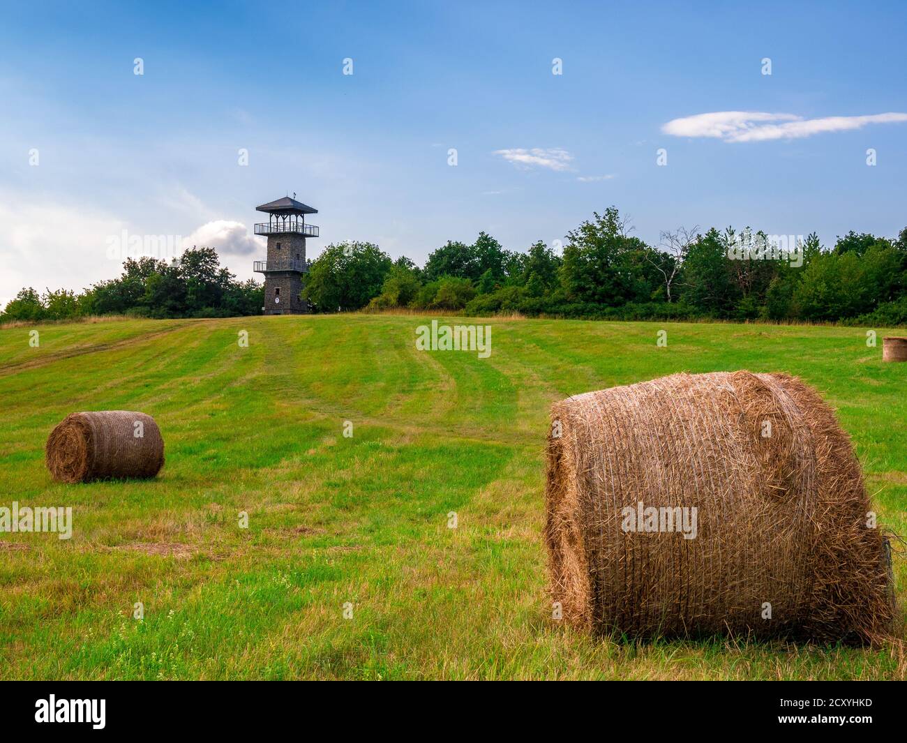 Eine Wiese mit runden Strohballen und einem Aussichtspunkt Turm am Rand Stockfoto